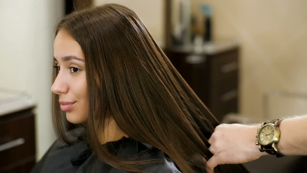 A stylist combing a client's long hair
